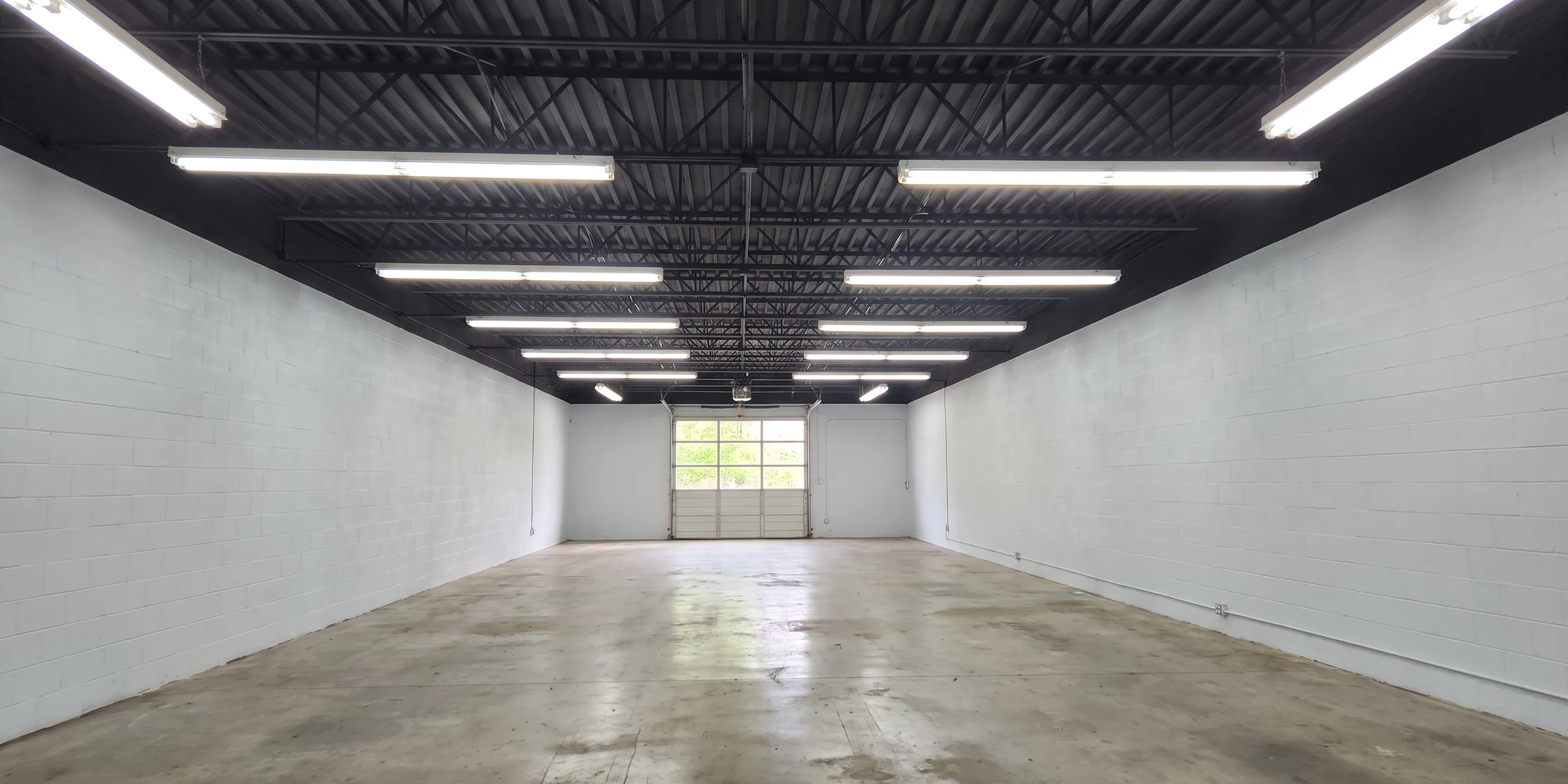 A finished commercial unit with the steel joist ceiling sprayed black above white block walls and strip lighting