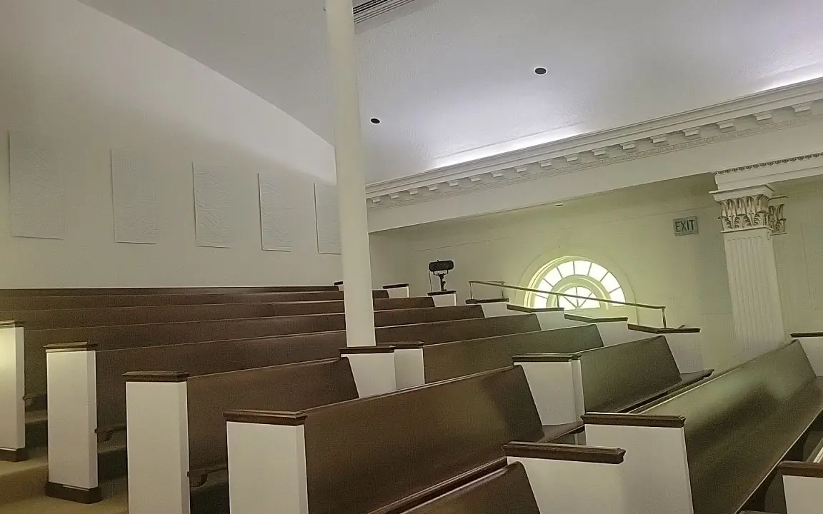 A church sanctuary in Chattanooga after commercial painting, with tall arched windows and wooden pews