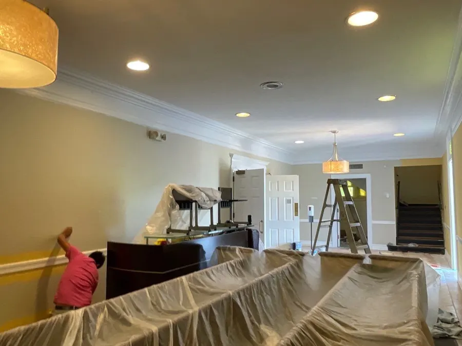 A commercial interior being painted with the furniture covered