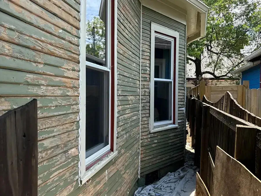 Weathered and failing wood siding on a house before repair