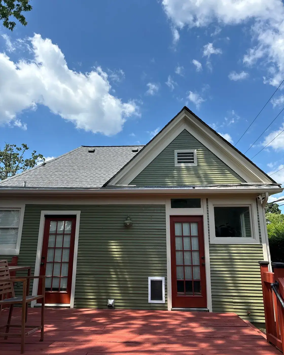 A wood-sided house repaired and repainted in green with red trim