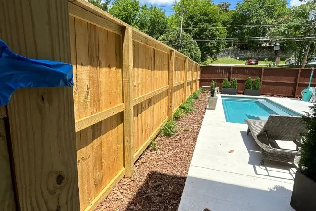 A new unstained cedar fence beside a swimming pool