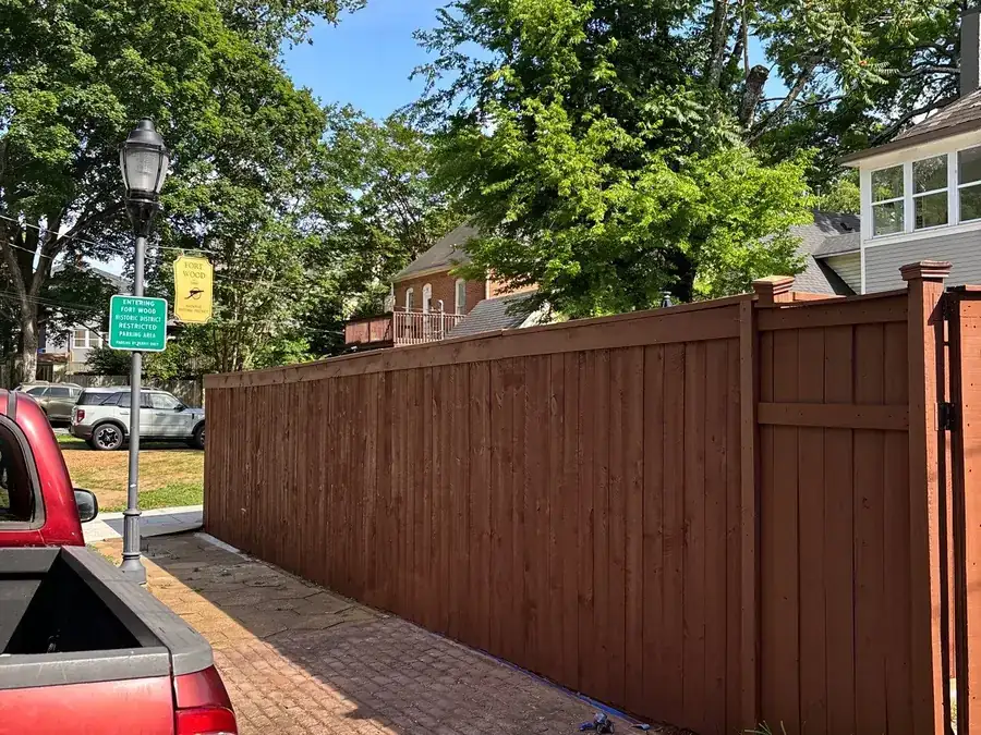 A stained wooden fence running along a street