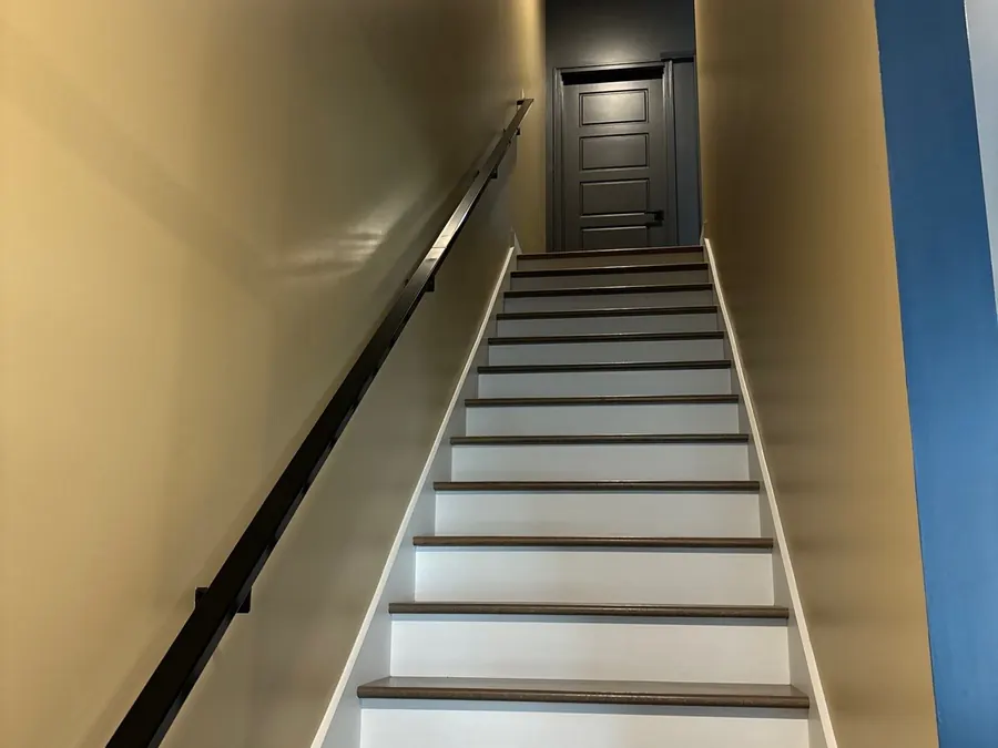 A repainted stairway with white risers and a dark handrail