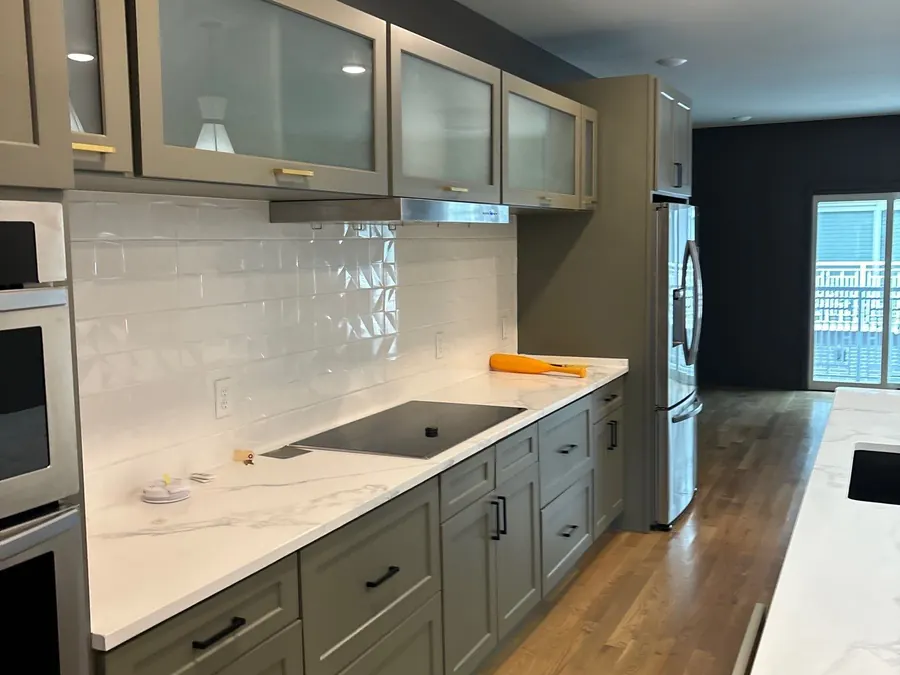 A repainted kitchen with a dark accent wall beyond