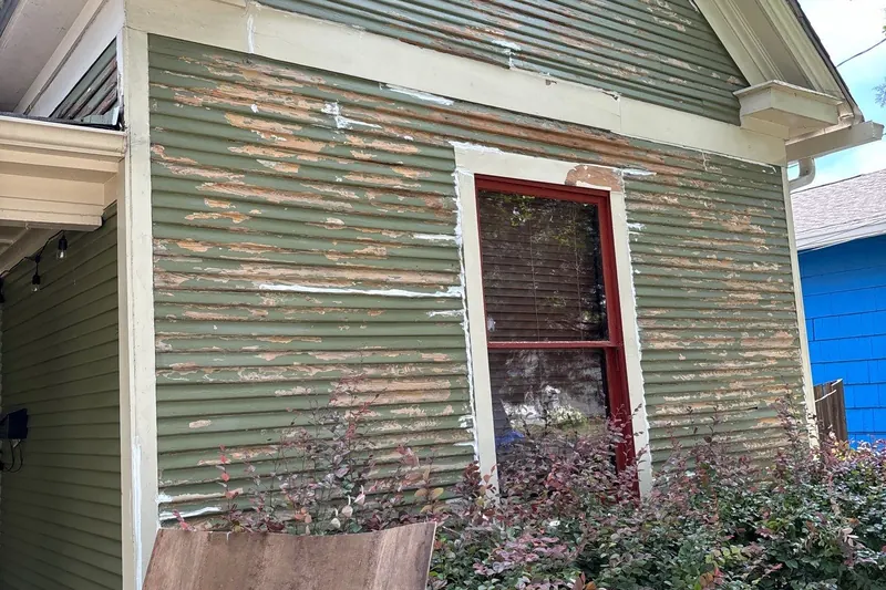 Deteriorated wood siding being repaired before painting