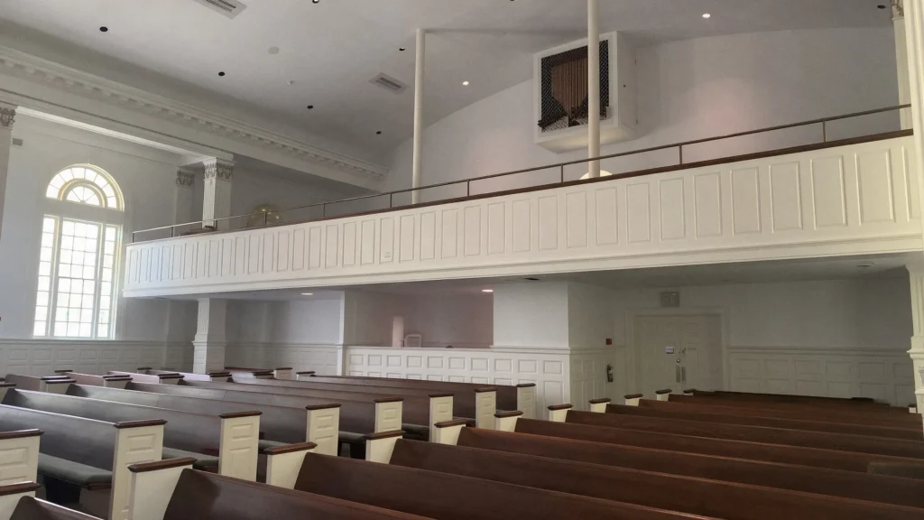 A church sanctuary with wooden pews and freshly painted white walls and ceiling